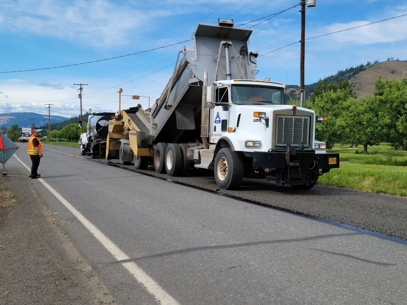 A dump truck working with a paving crew on a highway job
