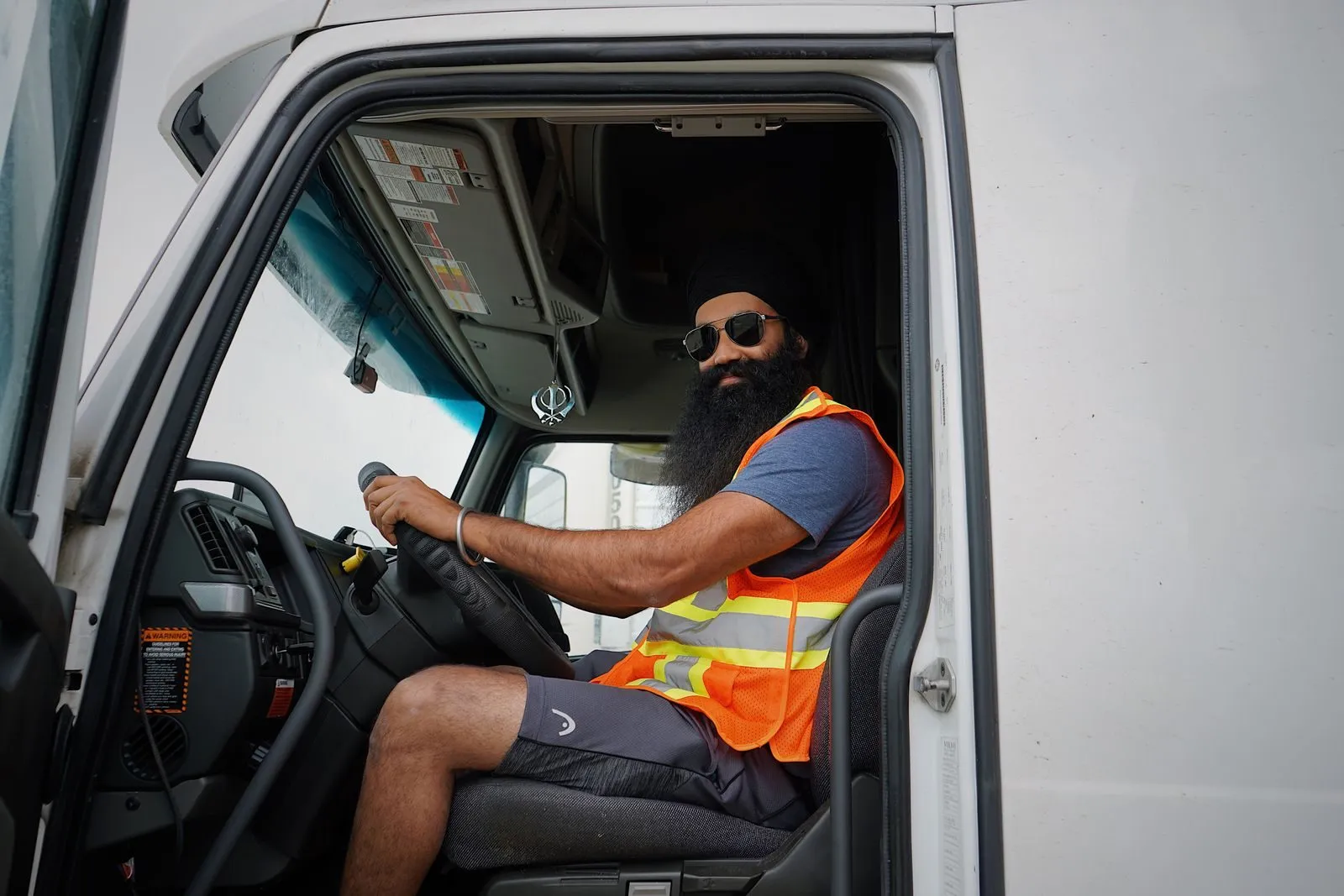 An owner-operator smiling from the cab of his truck