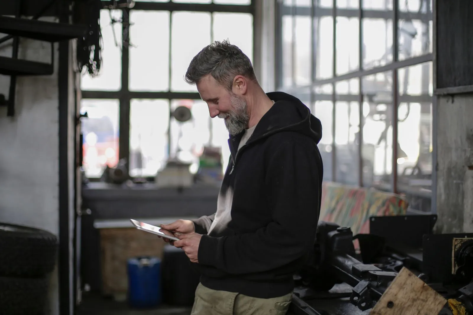 A smiling workshop owner checking a tablet in his metal shop