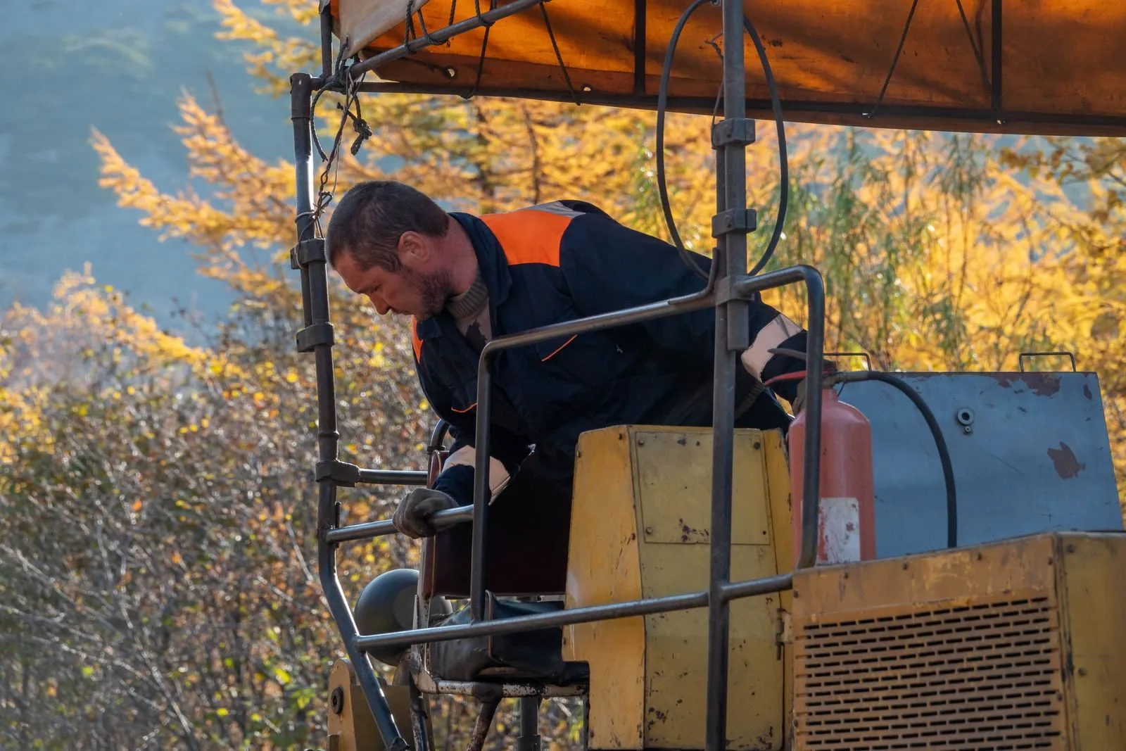 An equipment operator working at his machine on an autumn job site