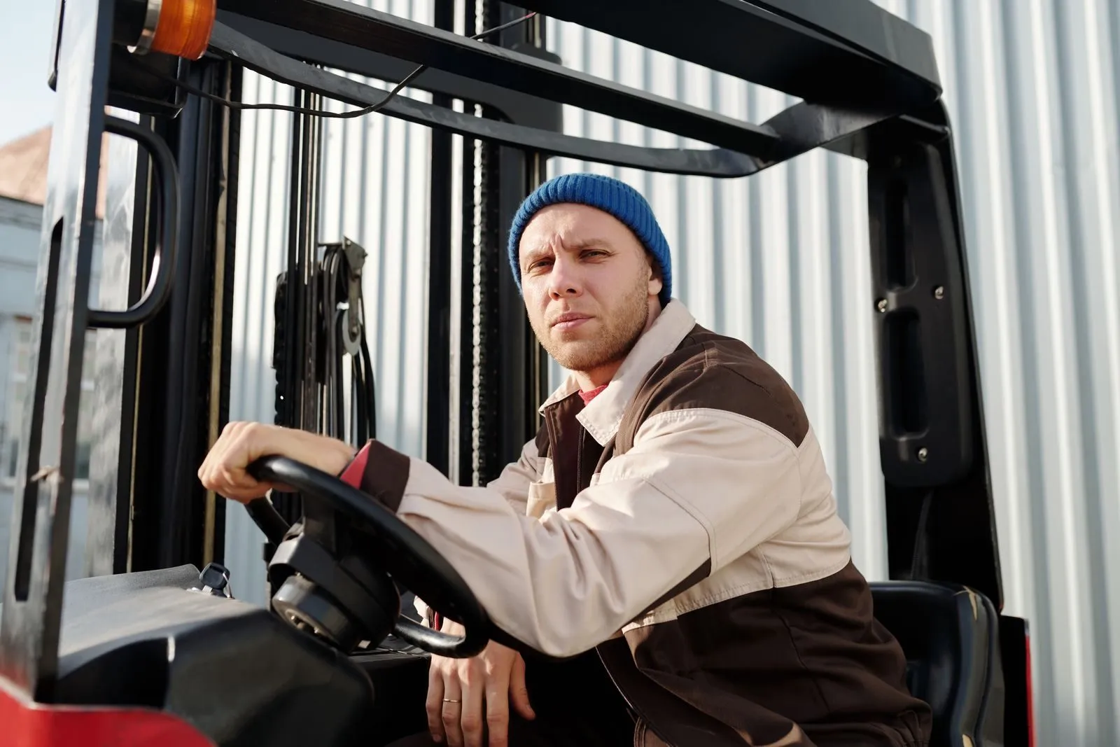 A forklift operator at the controls in a warehouse