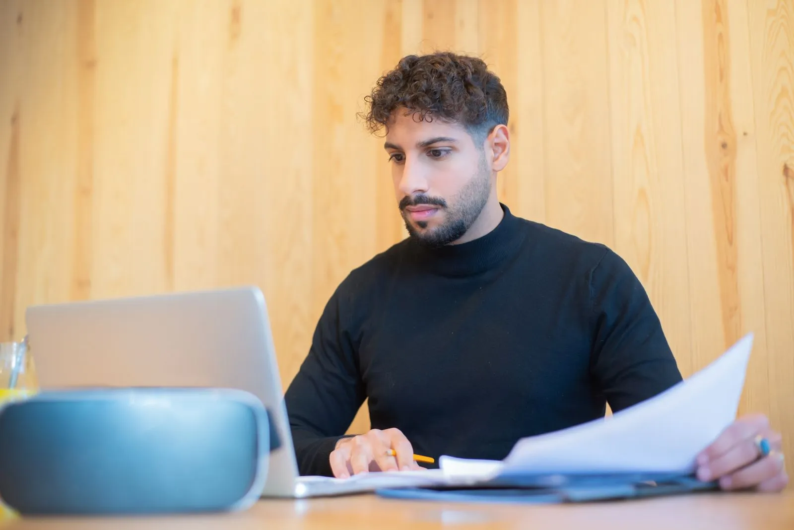 A business owner at a desk going through paperwork with a laptop open