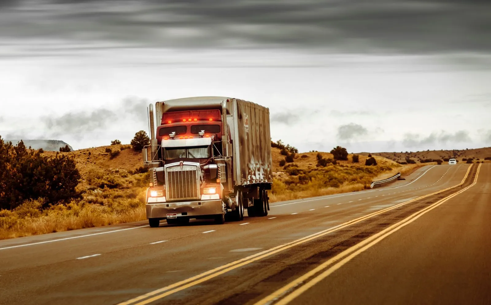 A red semi truck hauling a trailer on a highway at golden hour
