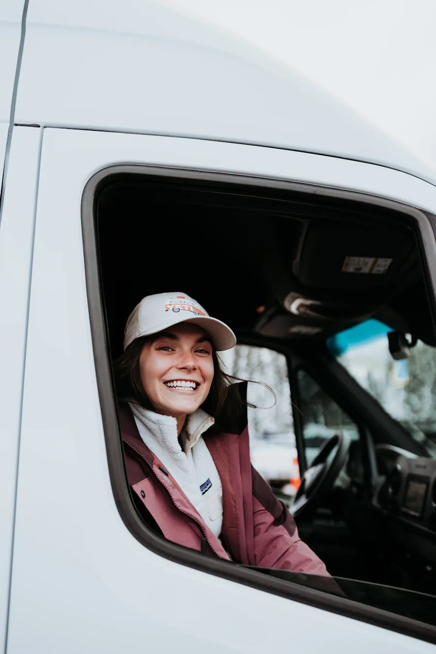 A smiling driver leaning out of her van window