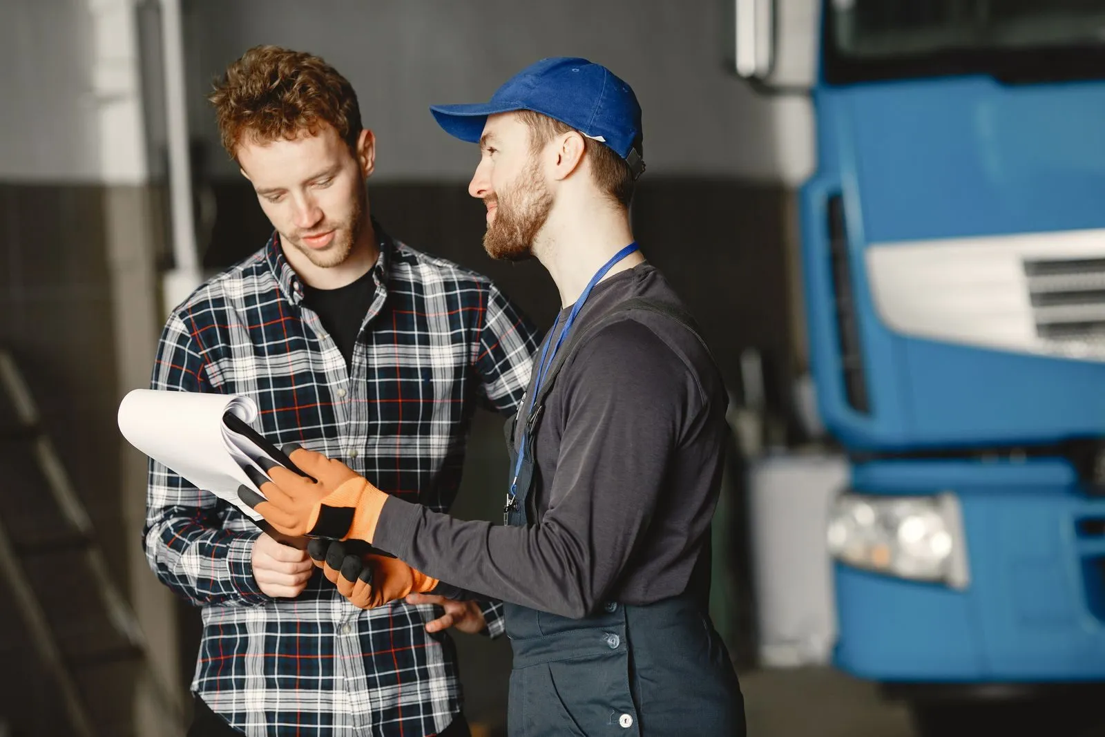 A buyer and a mechanic reviewing paperwork beside a used truck